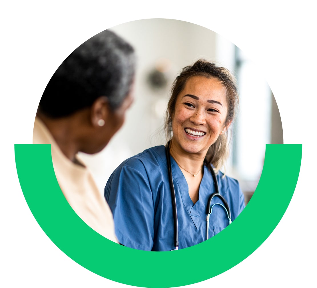 Lächelnde Pflegekraft, die sich mit einer/einem Patientin/Patienten unterhält